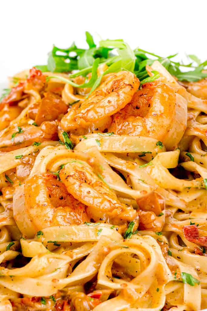 a close up image of Easy Shrimp Pasta with greens in the background