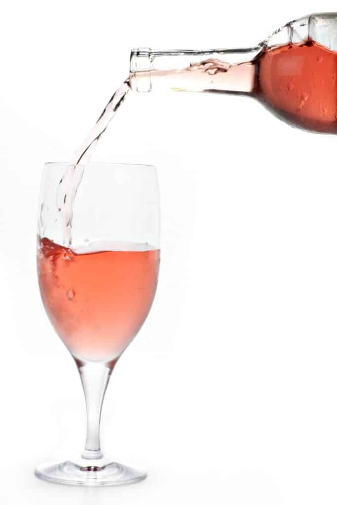 Zinfandel wine being poured into a glass with a white background