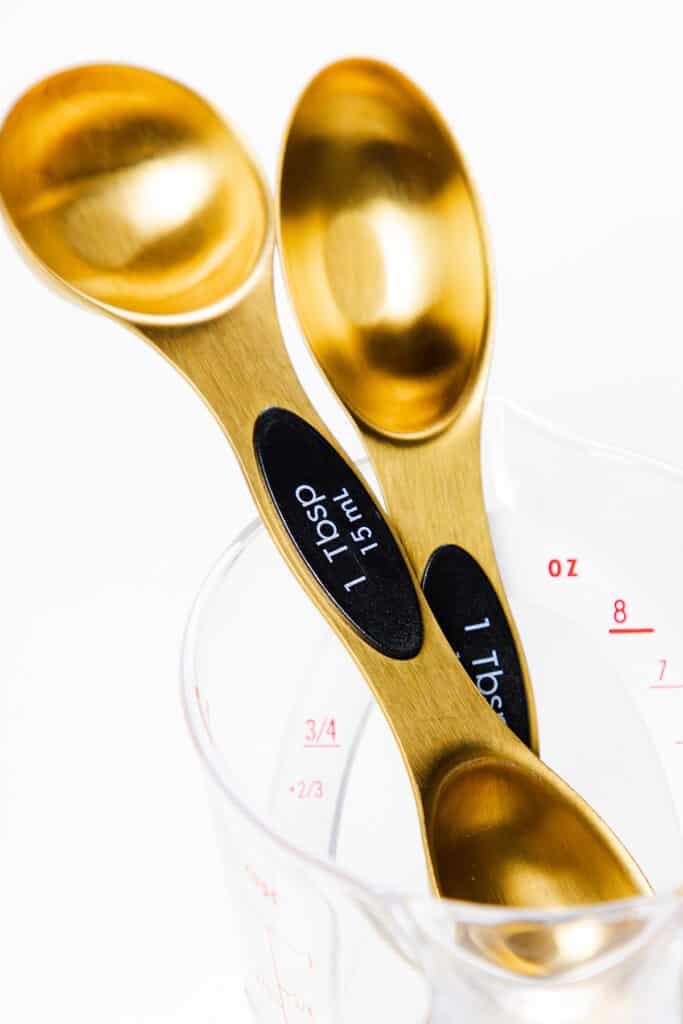a photo of two different shaped tablespoons in a measuring cup