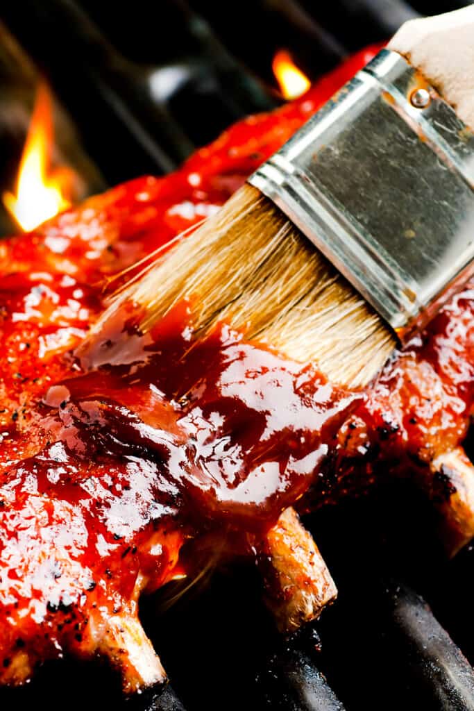 Carolina BBQ sauce being brushed onto ribs on a grill