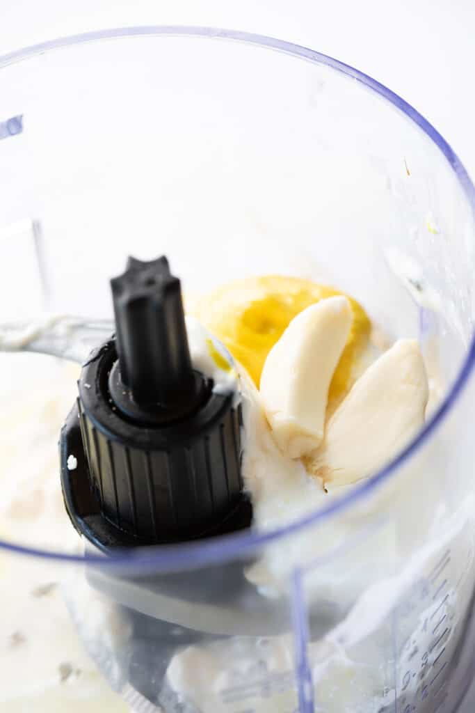 fresh garlic, mayonnaise, sour cream, lemon juice, salt, pepper, oil, mustard in the bowl of a food processor.