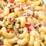 a close up image of a bowl of Amish Macaroni Salad with creamy sauce and chopped vegetables