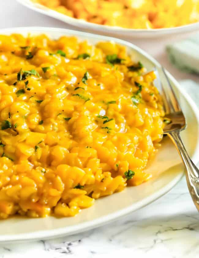 Saffron Risotto on a plate with a fork with another dish of risotto in the background