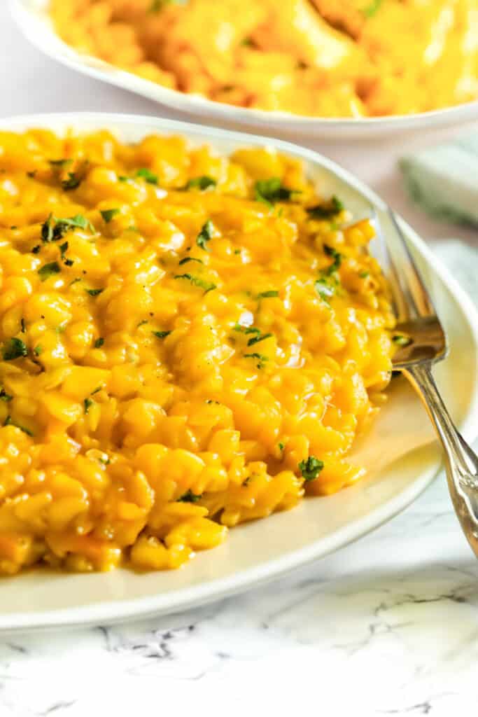 Saffron Risotto on a plate with a fork with another dish of risotto in the background