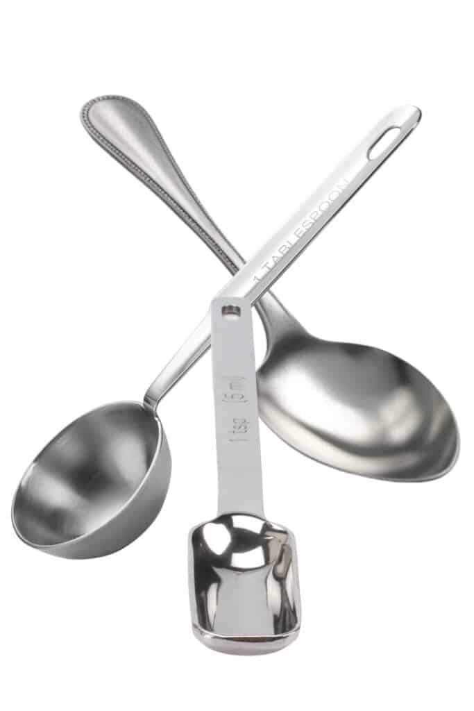 a stainless steel tablespoon and teaspoon measuring spoon and a dessert spoon with a white background