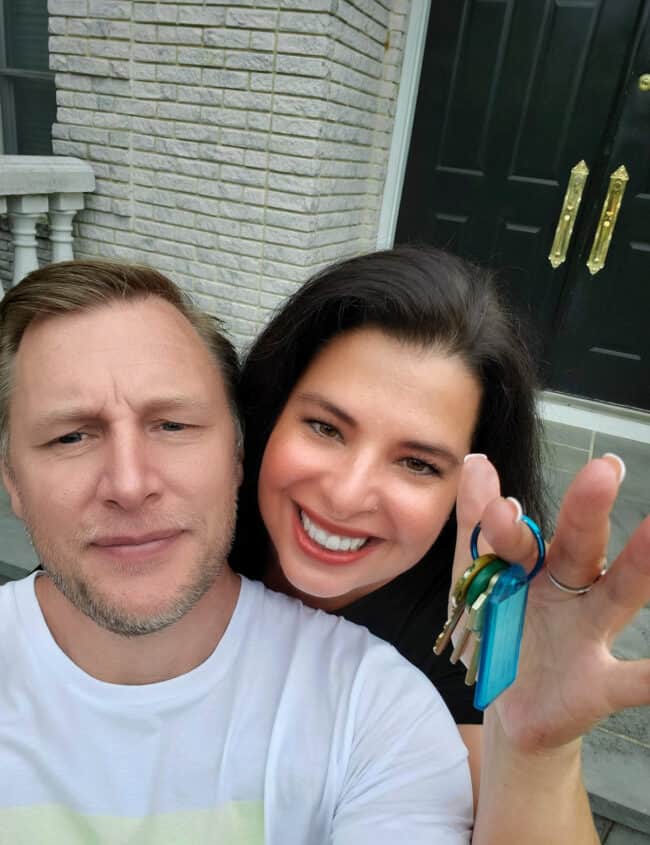 a picture of Erren & her husband with keys in her hands and a house in the background