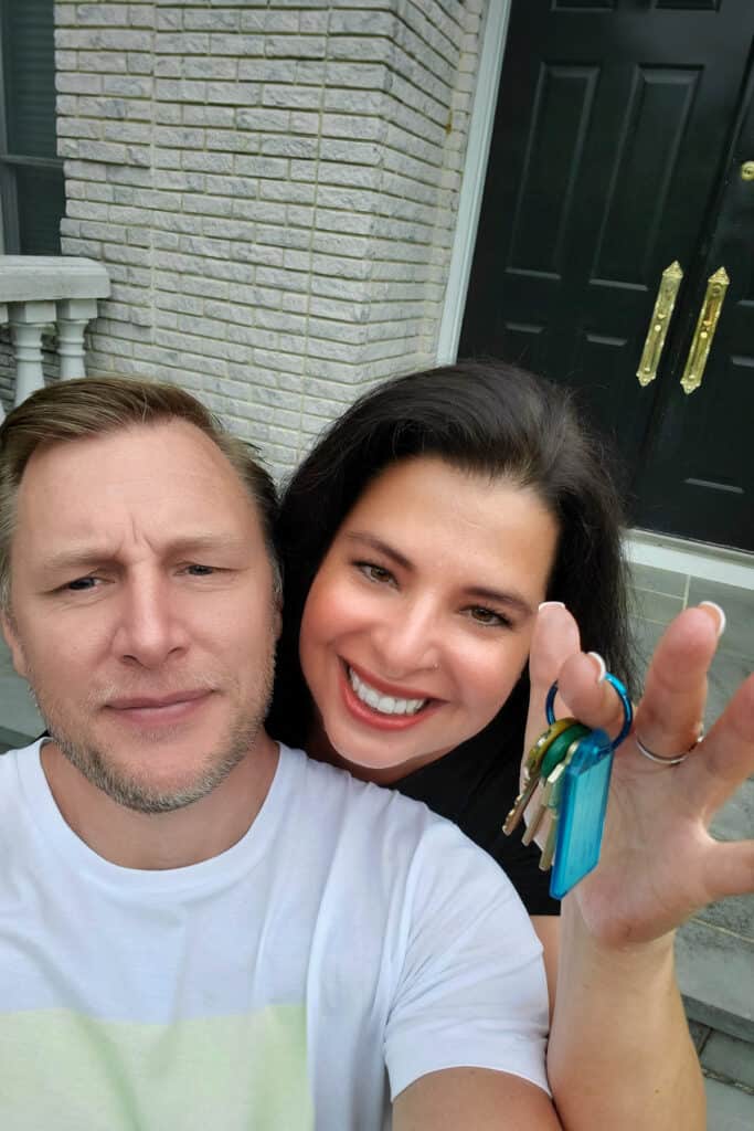 a picture of Erren & her husband with keys in her hands and a house in the background