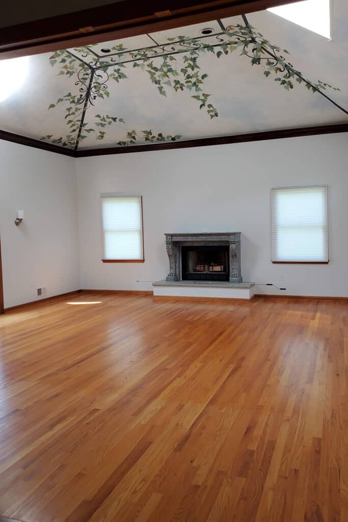 an empty great room with high ceilings and dated décor.