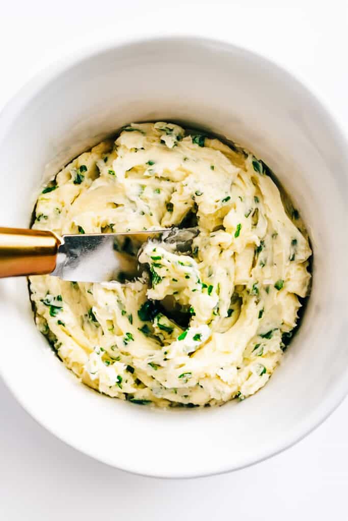 a bowl of herbs, garlic and butter mixed together