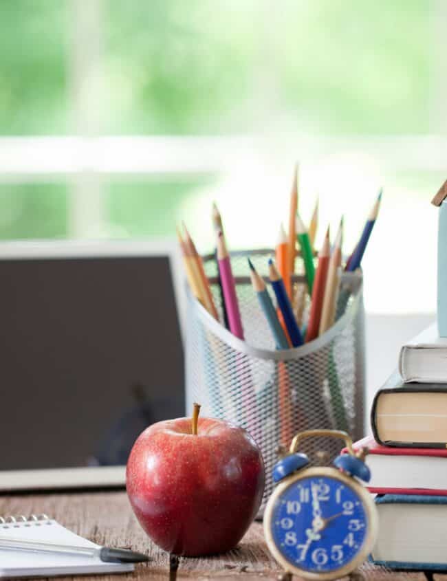 a homeschooling desk with pencils, books and a laptop