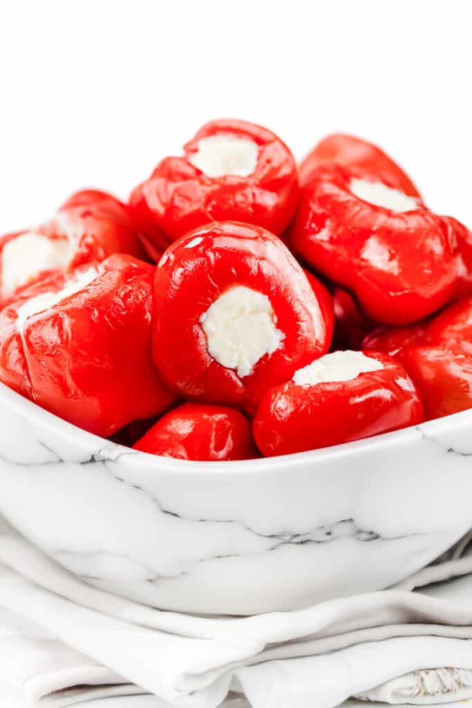 a white marble bowl of Stuffed Cherry Peppers and a cloth napkin under the bowl.