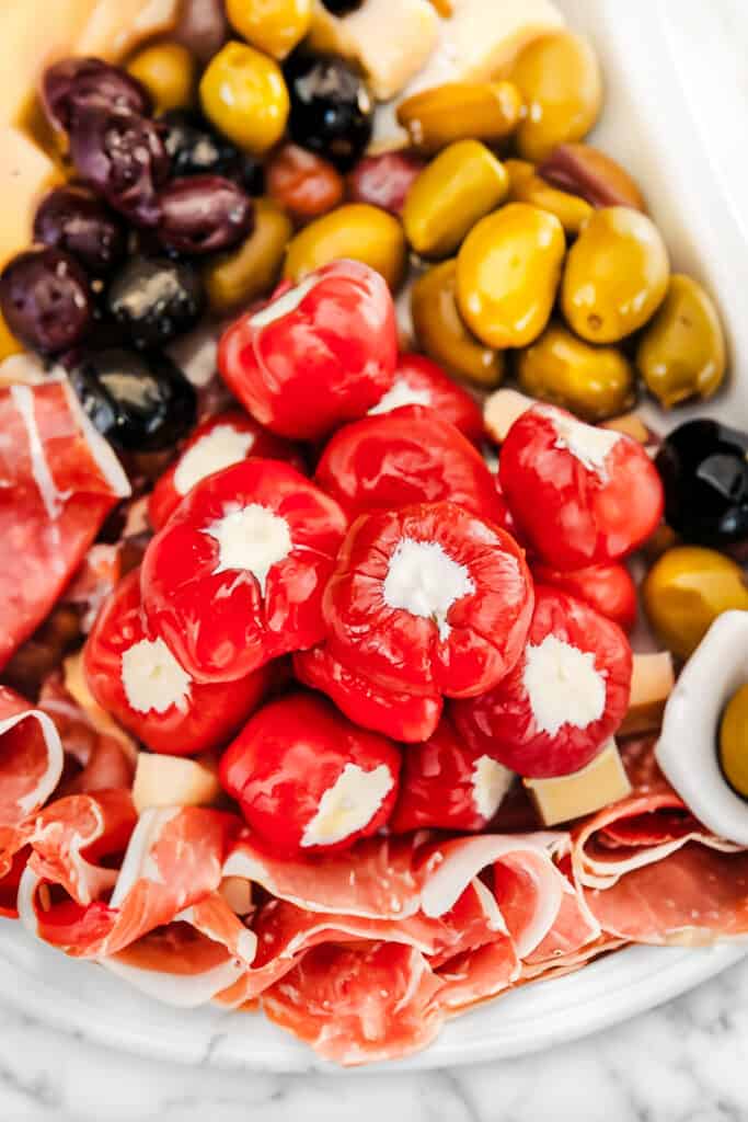 Stuffed Cherry Peppers on a platter of antipasto with cured meats and olives.