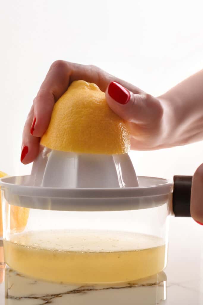 a hand pressing half a lemon onto a juicer.