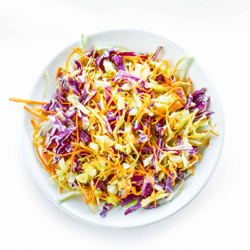the vinegar coleslaw tossed together in a white bowl.