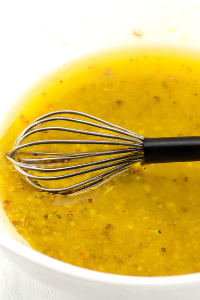 the dressing for vinegar coleslaw in a bowl with a whisk.