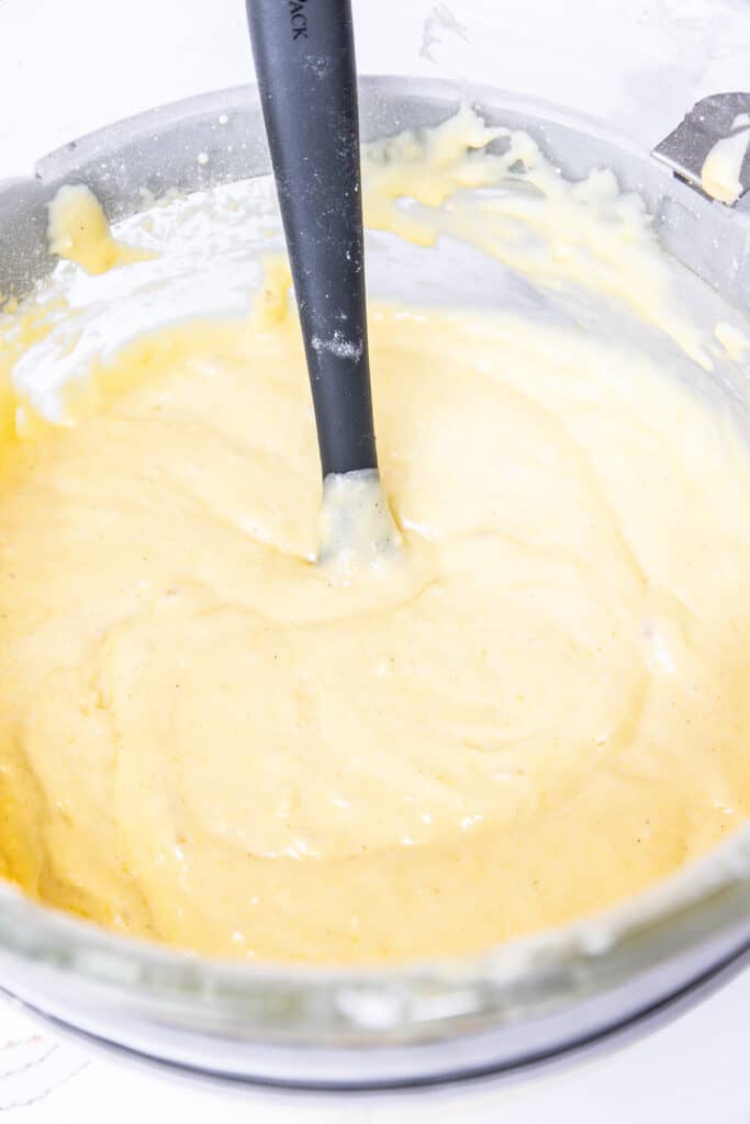 the mixed batter for the lemon curd cake in a mixing bowl with a spoon.