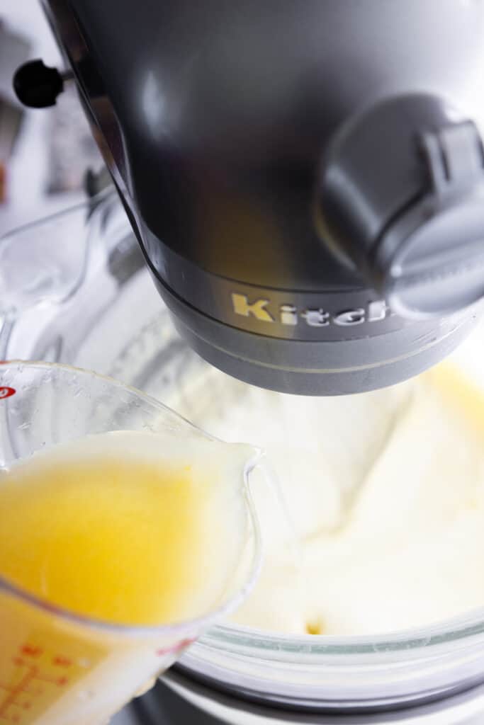 The lemon juice being poured into the cake batter for the lemon curd cake.