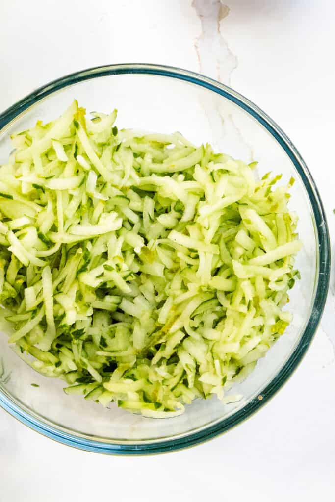 salted shredded cucumber in a glass bowl.