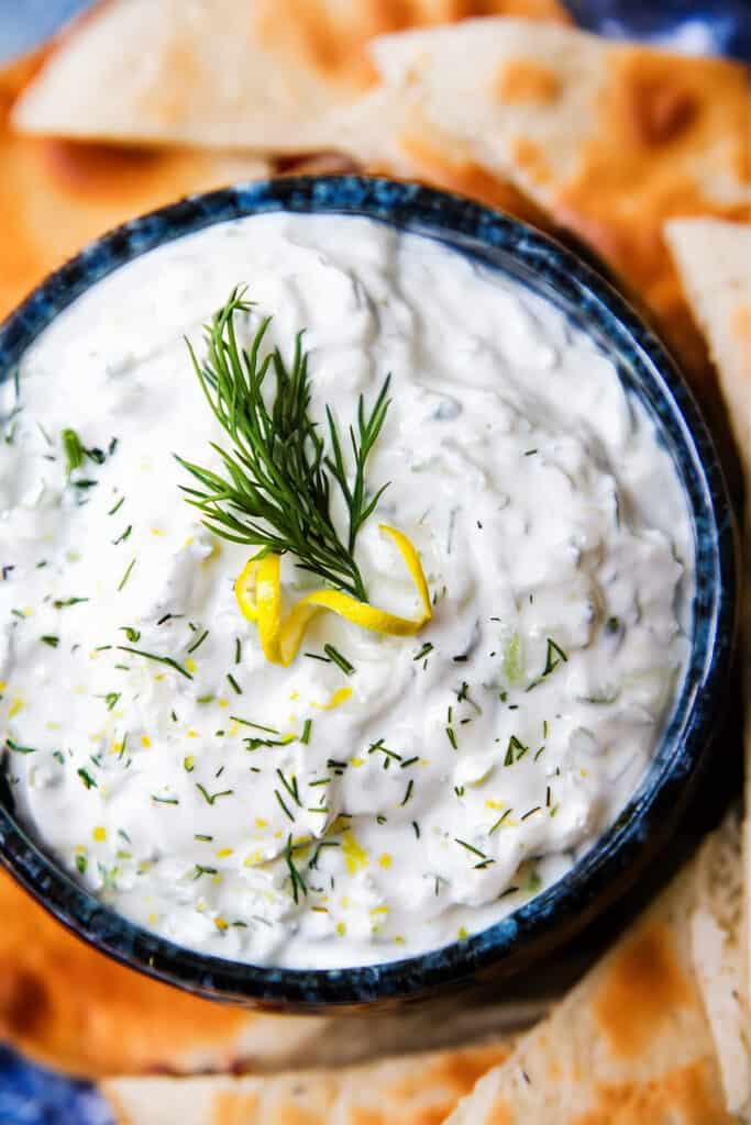 a bowl of Tzatziki topped with chopped dill and lemon zest.
