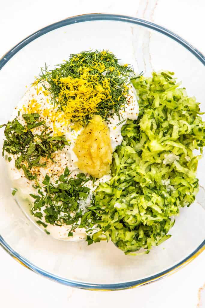 all of the ingredients for Tzatziki in a glass bowl.