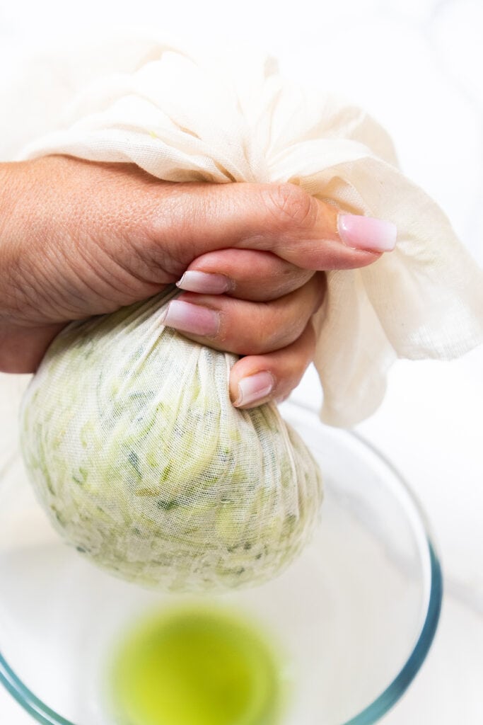 shredded cucumber being squeezed in cheesecloth.