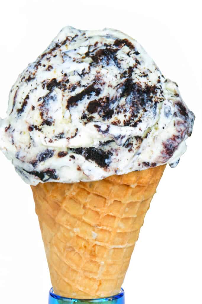 an ice cream cone topped with a scoop of cookies and cream ice cream.