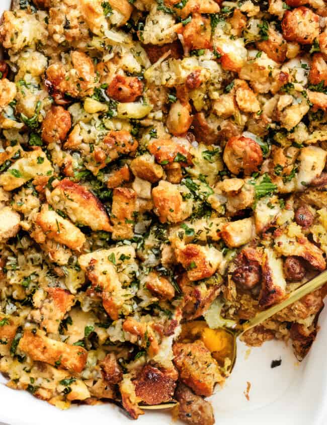 a close up image of a pan of sausage stuffing with a serving spoon in the pan.