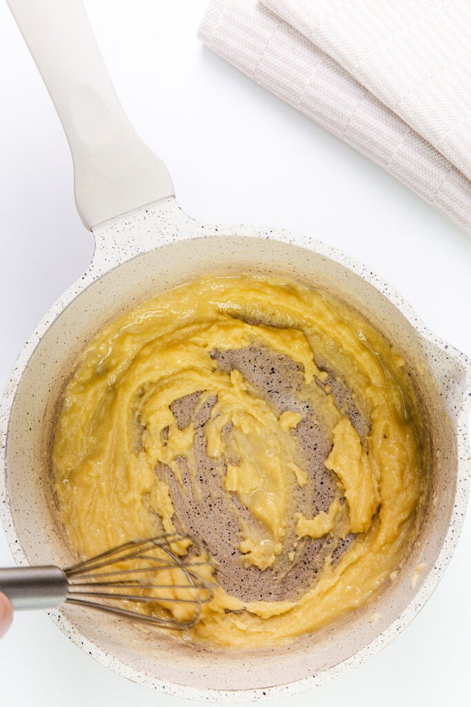 melted butter and flour being mixed in a bot with a whisk.