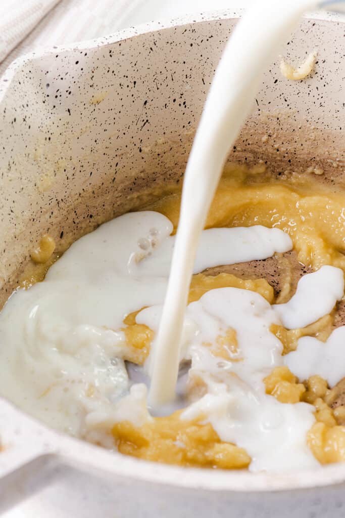 milk being poured into the butter and flour in the pan.