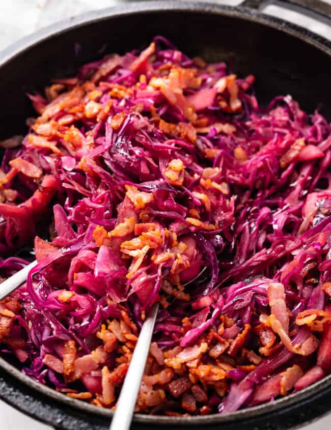 a close up image of braised cabbage scattered with crispy bacon.