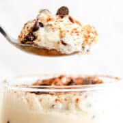 In the glass below, there's more of the creamy ricotta dessert, speckled with chocolate chips and a hint of cinnamon, being lifted by a spoon.