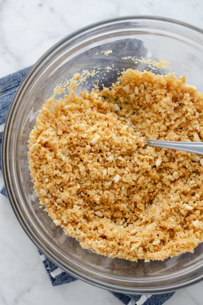 Crushed graham crackers and melted butter in a glass bowl.