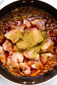 Chicken pieces with spices in a pot, ready to be cooked.