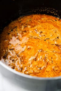 A creamy curry sauce beginning to cook in a black pot.