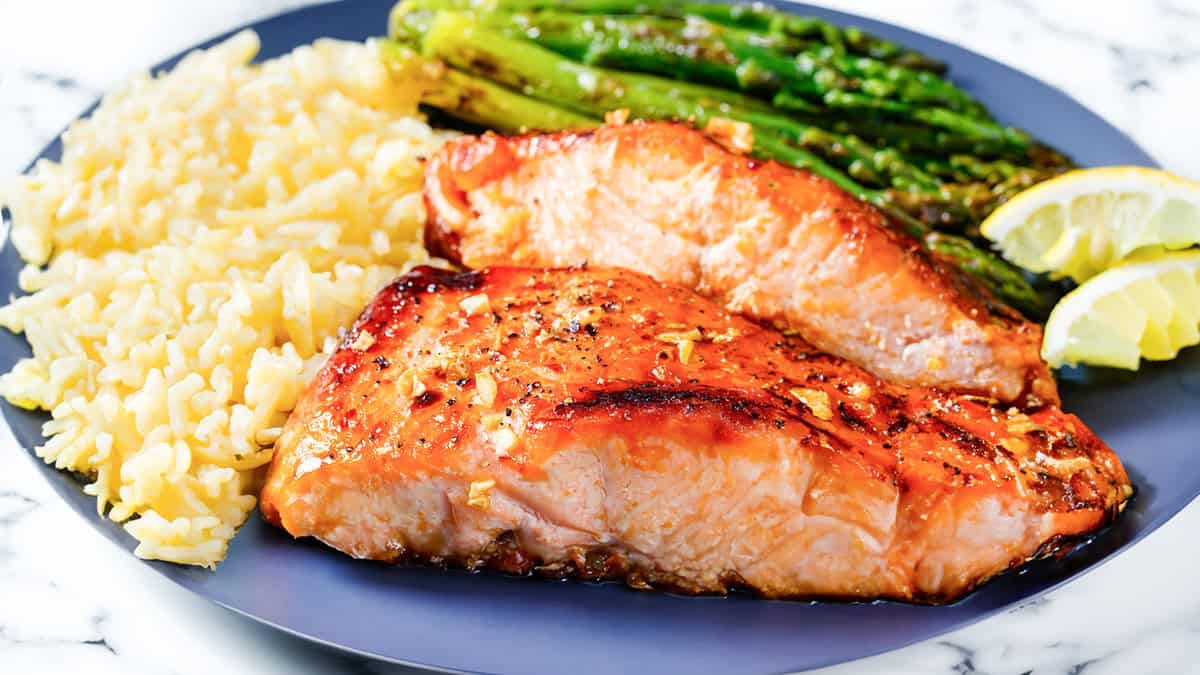 Two pieces of garlic butter salmon with roasted asparagus and rice pilaf.