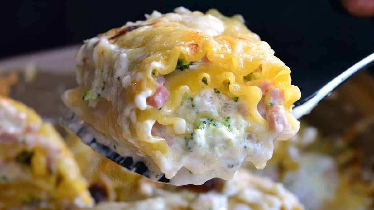 A close up image of a Ham and Broccoli Creamy Lasagna Roll Up being served from a baking dish.