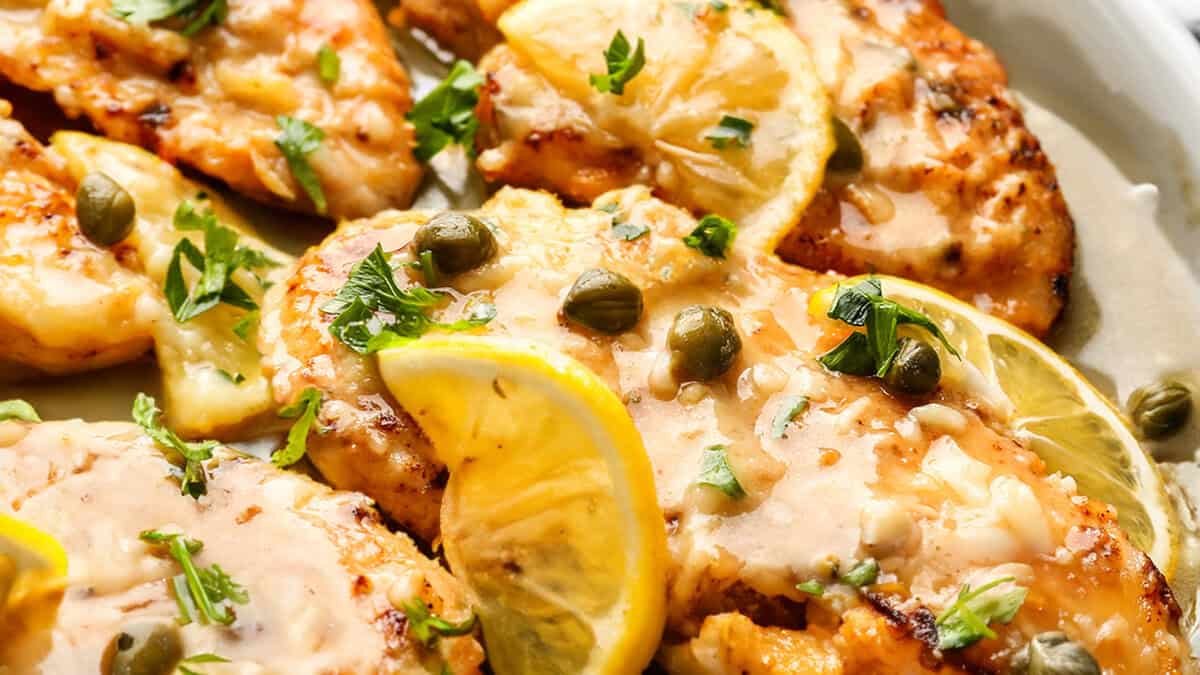 A plate of Fish Piccata garnished lemon and capers.