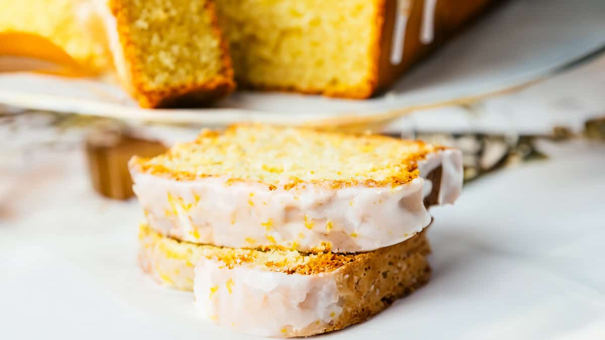 A sliced lemon pound cake with icing and lemon zest.