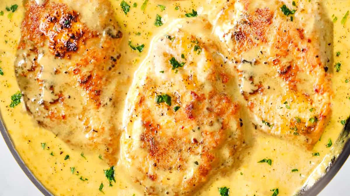 A close up of a pan of chicken in mustard sauce.