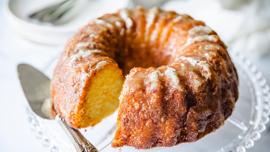 An orange Bundt cake on a glass cake stand.