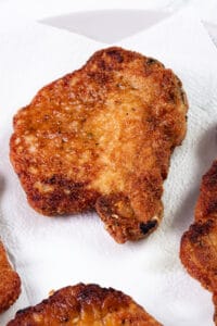 Golden and crispy panko-breaded pork chops resting on paper towels to drain excess oil.