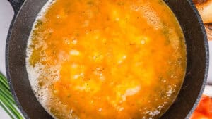 A close-up of a black skillet with the egg mixture beginning to cook.