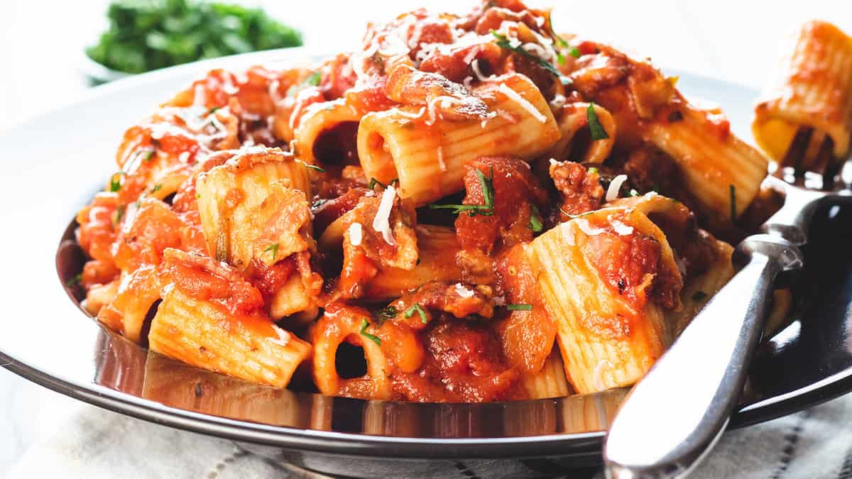 A heaping bowl of pasta with Amatriciana Sauce topped with grated cheese.