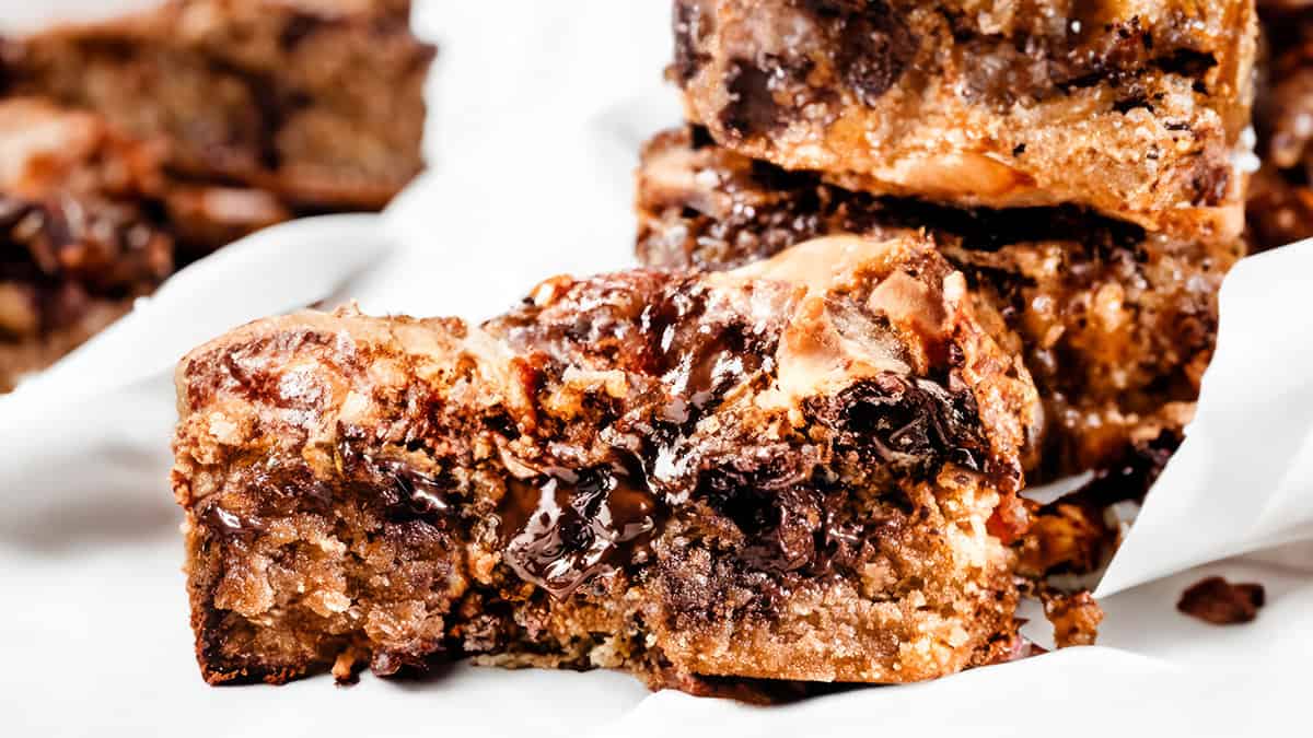 A close up image of a chocolate chip blondie with a gooey center exposed.