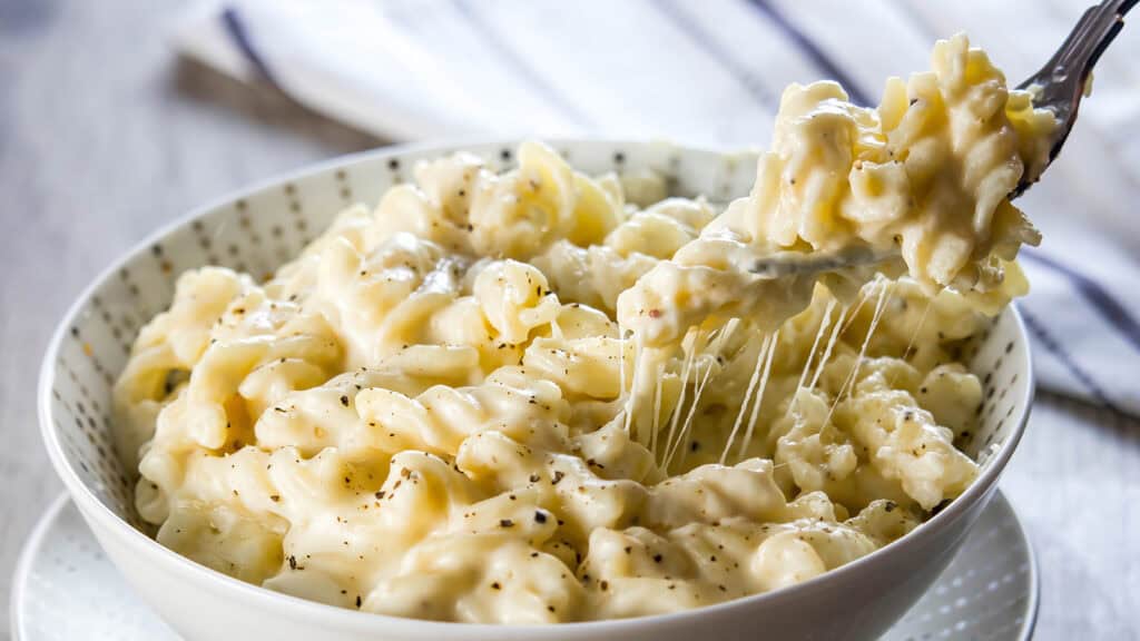 A fork digging into a big bowl of Homemade Creamy Mac and Cheese