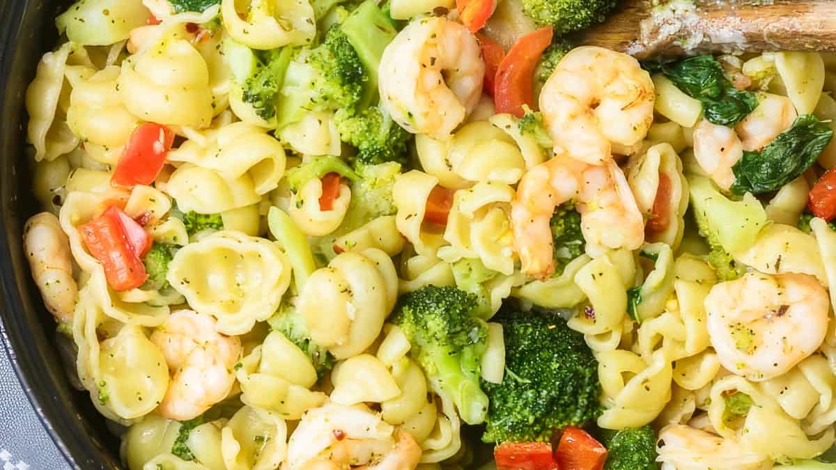 a close up image of broccoli pasta with shrimp in a pan.