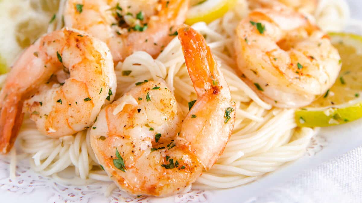 A plate full of shrimp scampi and spaghetti sprinkled with fresh chopped parsley.