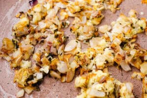 Onion and herbs frying in a pan.