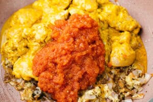 Marinated chicken, the fried onions and tomato puree read to be mixed in a pan.