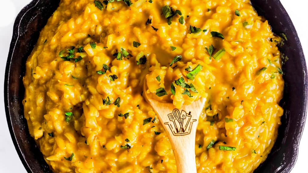 Saffron Risotto in a black pan with a wooden spoon.
